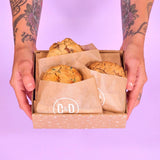 3 x New York Cookies The Birthday Box with three chunky cookies in branded packaging held by tattooed hands